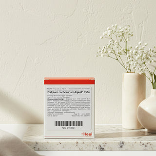 Packaging of Calcium Carbonicum Injeel Forte ampoules with product information and branding visible.